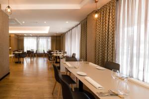 拉科鲁尼亚阿文尼达酒店的餐厅设有白色的桌椅和窗户。