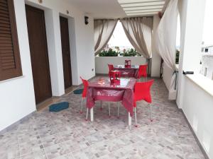 莱乌卡B&B MareIncantato的一间用餐室,配有红色的椅子和桌子