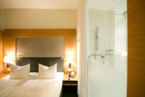 因斯布鲁克赛勒酒店的一间卧室配有一张带电话和淋浴的床
