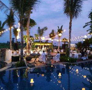 SiyutRoom in Villa - Kori Maharani Villas - Suite Lagoon 3的夜间带桌子和棕榈树的度假村游泳池