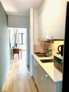 安特卫普Sam in Antwerp的厨房铺有木地板,配有白色橱柜。