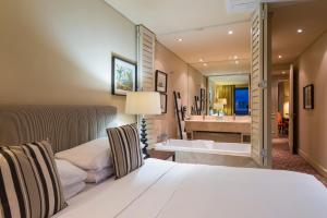 德班Royal Palm Hotel的一间卧室配有一张床,浴室设有浴缸