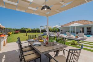 VanátonMadini Luxury villa with private heated pool的庭院配有桌椅和遮阳伞。