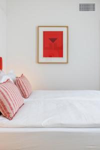 洛迦诺Villa Rossella的一张带两个枕头的白色床和一张墙上的照片
