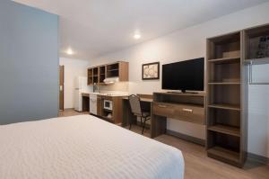 林奇堡WoodSpring Suites Lynchburg VA的酒店客房配有一张床和一张书桌及一台电视