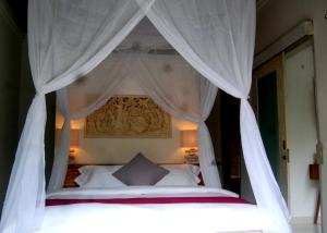 BalianBalian Bliss Retreat Bungalow & Villas的卧室配有带白色窗帘的天蓬床