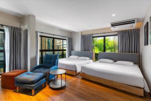 曼谷萨格布小巢酒店的酒店客房,配有两张床和椅子