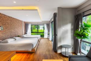 曼谷萨格布小巢酒店的一间卧室设有三张床和砖墙