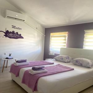 莫斯塔尔Purple rooms的一间卧室配有一张大床和毛巾