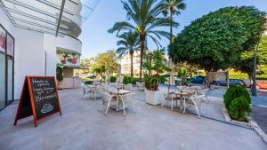 马贝拉Hapimag Resort Marbella的一间设有桌椅的餐厅,种植了棕榈树