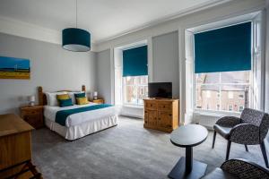 蒙特罗斯The Juniper Rooms的一间卧室配有一张床和两个带蓝百叶窗的窗户。