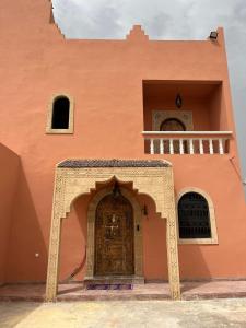 索维拉Riad Aïcha Addi - Poolside - Traditional Moroccan的橙色的建筑,设有门和阳台