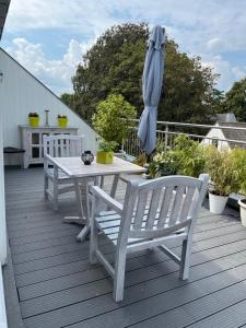 海斯特奥普登贝尔赫Rooftop terrace suite的甲板上配有白色的桌椅和遮阳伞