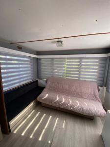 林古泽塔Bungalow confortable proche de la mer的一张位于带两个百叶窗的房间的床铺