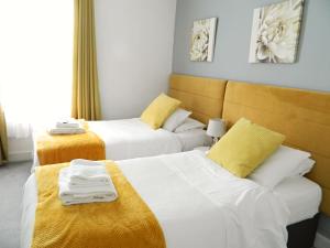 沃里克沃里克金斯赫德酒店的黄色调的酒店客房内的两张床