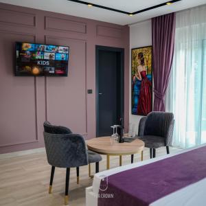 地拉那Jata Crown Hotel的客厅配有桌椅和电视。