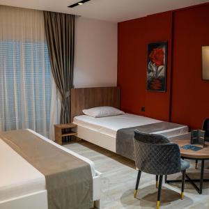 地拉那Jata Crown Hotel的一间卧室配有两张床、一张桌子和一把椅子
