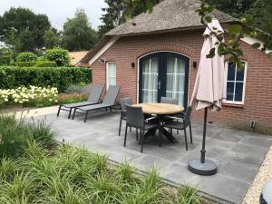 埃尔默洛Villa Felix with sauna in Ermelo的庭院配有桌椅和遮阳伞。