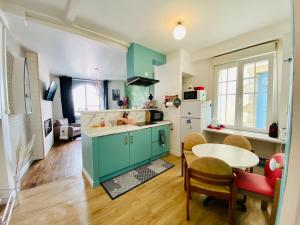 勒帕莱Appartement Vert du Palais - Relaxation Centrale的厨房配有绿色橱柜和桌椅