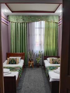 塔什干House4you的客房设有两张床和一个带绿色窗帘的窗户。