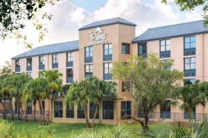 肯代尔The Palms Inn & Suites Miami, Kendall, FL的一座棕榈树的办公楼