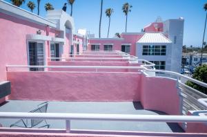 洛杉矶Days Inn by Wyndham Santa Monica的一群棕榈树的粉红色和白色建筑