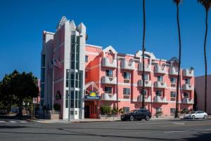 洛杉矶Days Inn by Wyndham Santa Monica的一座大型红色建筑,前面有汽车停放