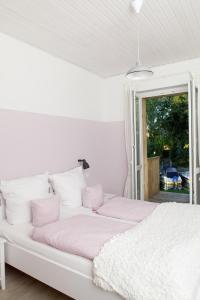 哈弗尔河畔勃兰登堡Wassersportzentrum Alte Feuerwache的白色的床、粉色和白色枕头以及窗户