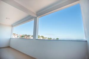 圣托梅-达斯莱特拉斯Souza Reis Apart - Unidade 1的一间设有大窗口的客房,背景是大海