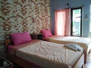 沙美岛塔尼沙美岛旅馆的配有粉红色枕头的客房内的两张床