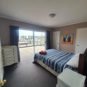 陶波The Retreat Taupo的一间卧室设有一张床和一个阳台的窗户。