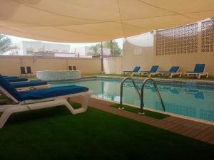 拉斯阿尔卡麦Oasis Hotel Apartment的一个带躺椅和遮阳伞的游泳池