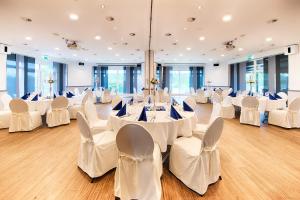 施图尔Select Hotel A1 Bremen-Stuhr的宴会厅配有白色的桌子和白色的椅子