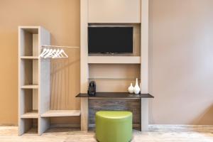 不莱梅不莱梅城市优选酒店 的一间带电视和绿色凳子的客厅