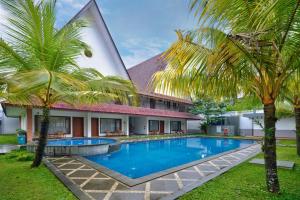 BanyumasHadipriyanto Homestay的棕榈树屋前的游泳池