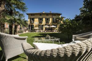 卡罗纳Swiss Historic & Garten Hotel Villa Carona的院子里带藤椅和桌子的房子