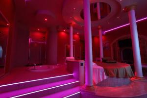 埃博利Alcova Suite&Relax的一间设有粉红色照明、一张床和浴缸的客房