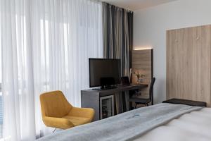 柏林柏林斯皮格尔腾精选酒店的酒店客房配有一张床、一张书桌和一台电视。