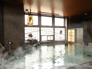 冈山Dormy Inn Okayama Natural Hot Spring的大型游泳池,位于带大窗户的房间内