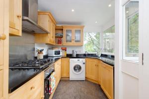 爱丁堡ALTIDO 3-bed Meadows flat near Castle的厨房配有木制橱柜、洗衣机和烘干机