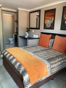 EikenhofKlein Kavali Studio's的一间卧室配有一张带橙色毯子的大床