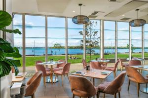 麦夸里港麦夸里港莱吉斯酒店的餐厅设有桌椅和大窗户。