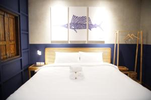 芭堤雅市中心Tali-Yailai Hostel的卧室配有一张白色大床和两条毛巾