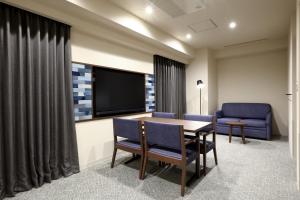 冈山Dormy Inn Okayama Natural Hot Spring的一间配备有桌椅和电视的会议室