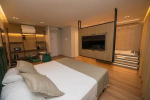 圣路易斯-贡萨加Origens Hotel的卧室配有一张白色大床和一台平面电视。