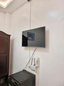 塔里萨伊MJ Pension House的挂在墙上的电视,配有打印机