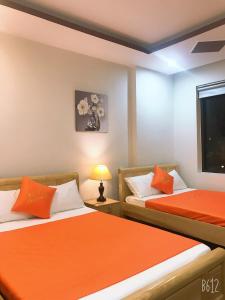 岘港Bao Tran Homestay的配有橙色床单的客房内的两张床