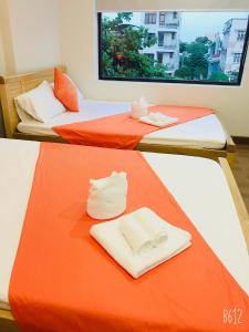 岘港Bao Tran Homestay的橙色和白色的客房内的两张床