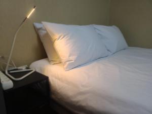 仁川市TreehouseUnseo GuestHouse的一张带白色枕头的床和一张桌子上的台灯