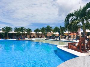 威廉斯塔德The Ritz Village的一个带椅子和棕榈树的度假村游泳池